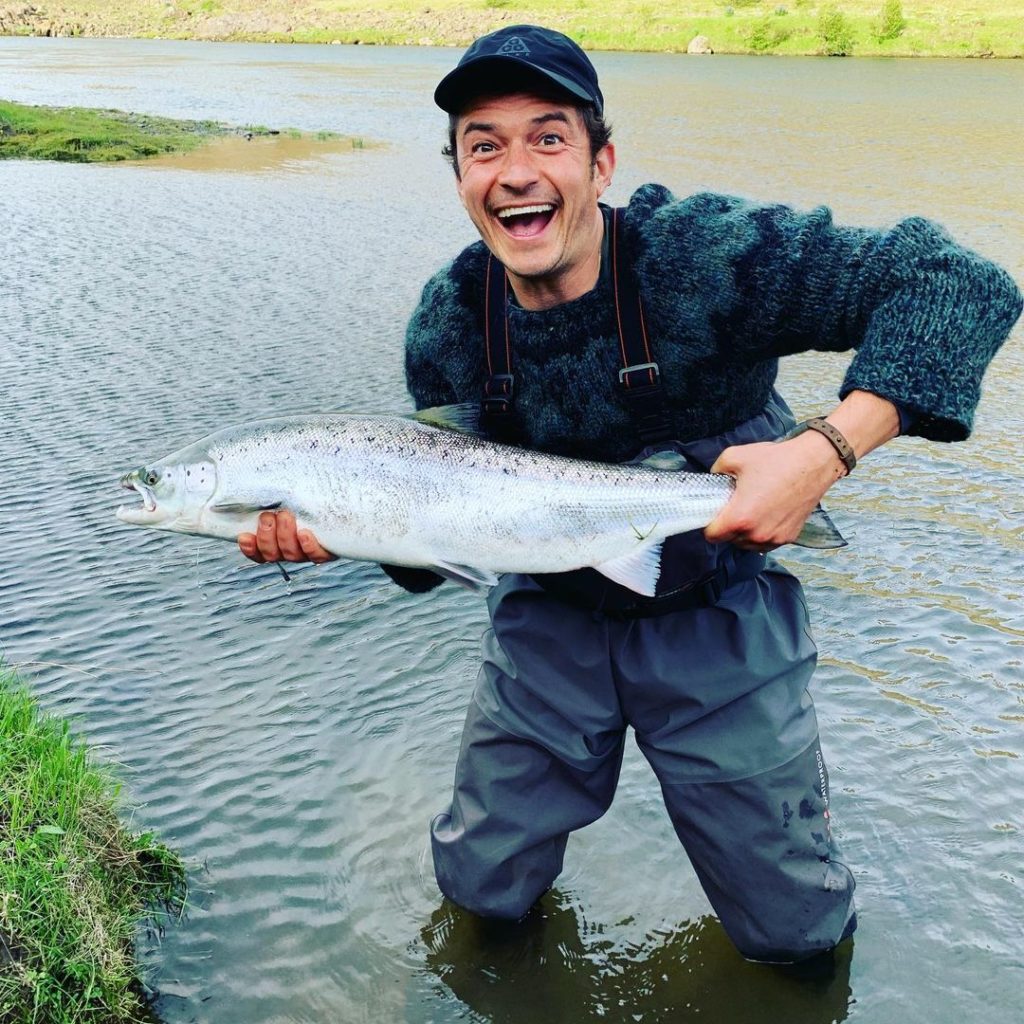 актер Орландо Блум на рыбалке. В руках большая рыба.