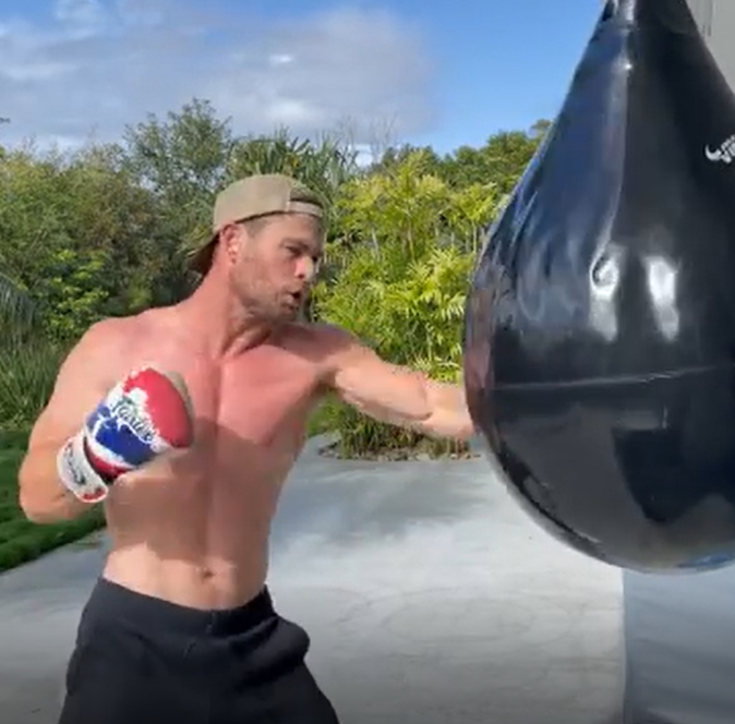Крис Хемсворт тренируется и бьет боксерскую грушу.