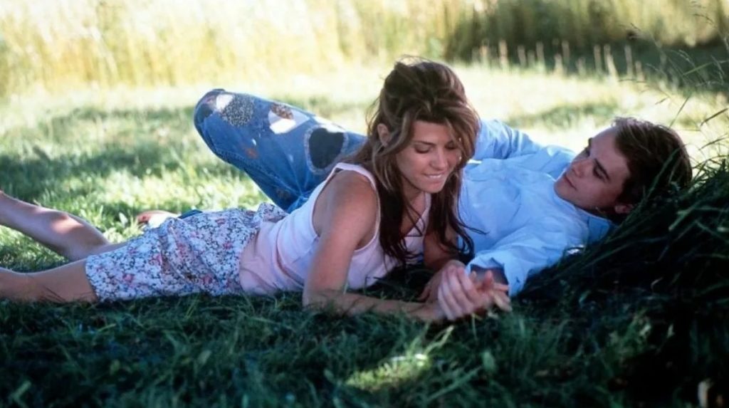 Киноактер Ник Стал лежит на траве рядом с девушкой.